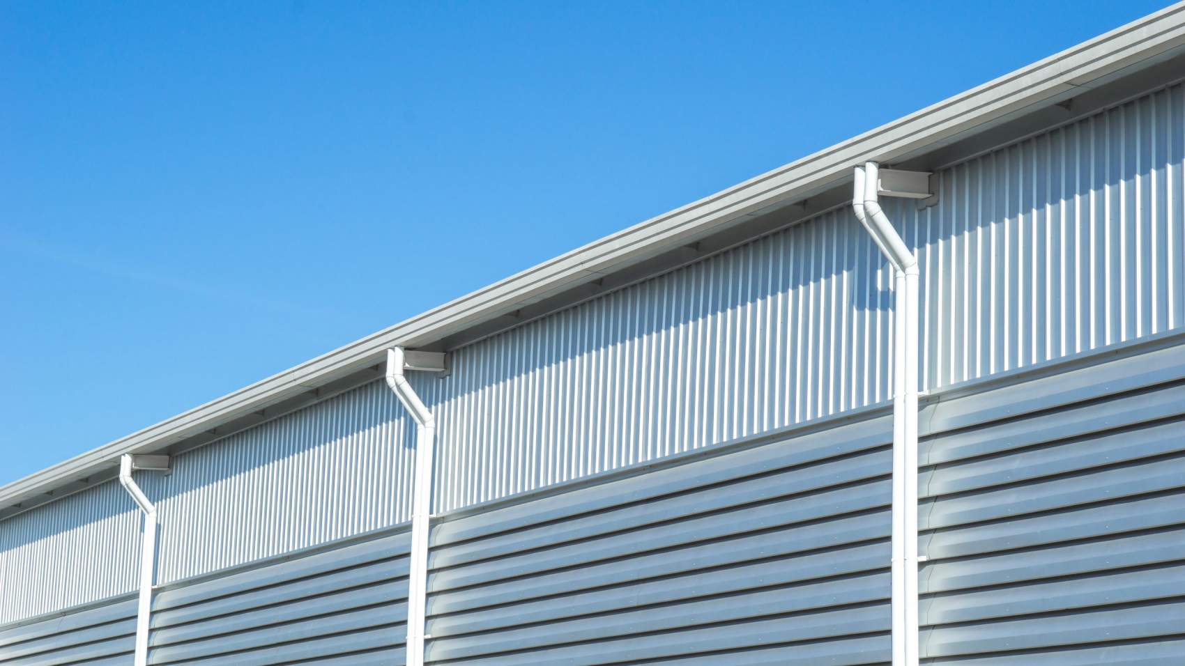 Factory warehouse and industrial concept - Close up wall and roof of Factory or warehouse building in industrial estate with blue sky and copyspace