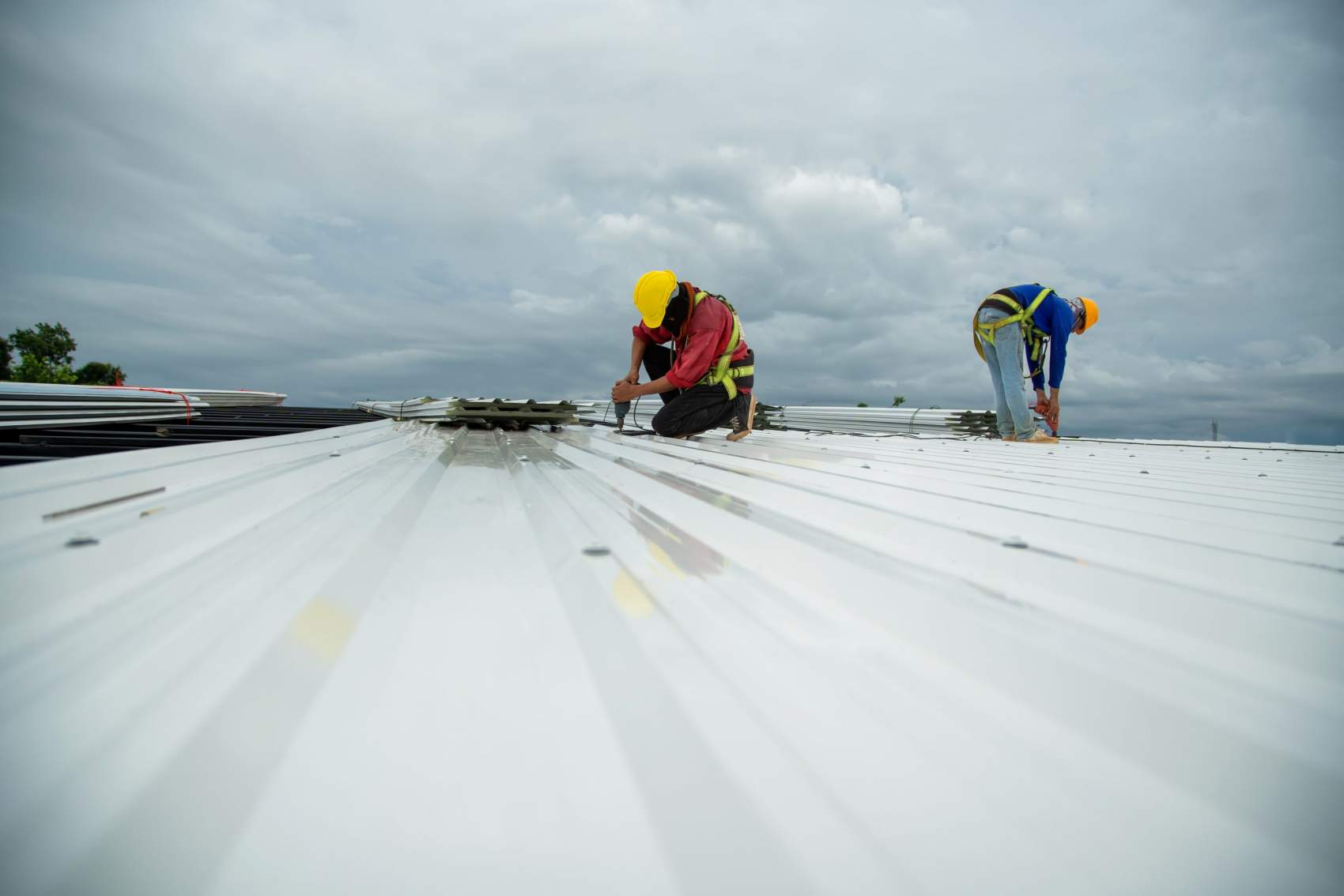 Asian construction worker holding metal sheet installation tool