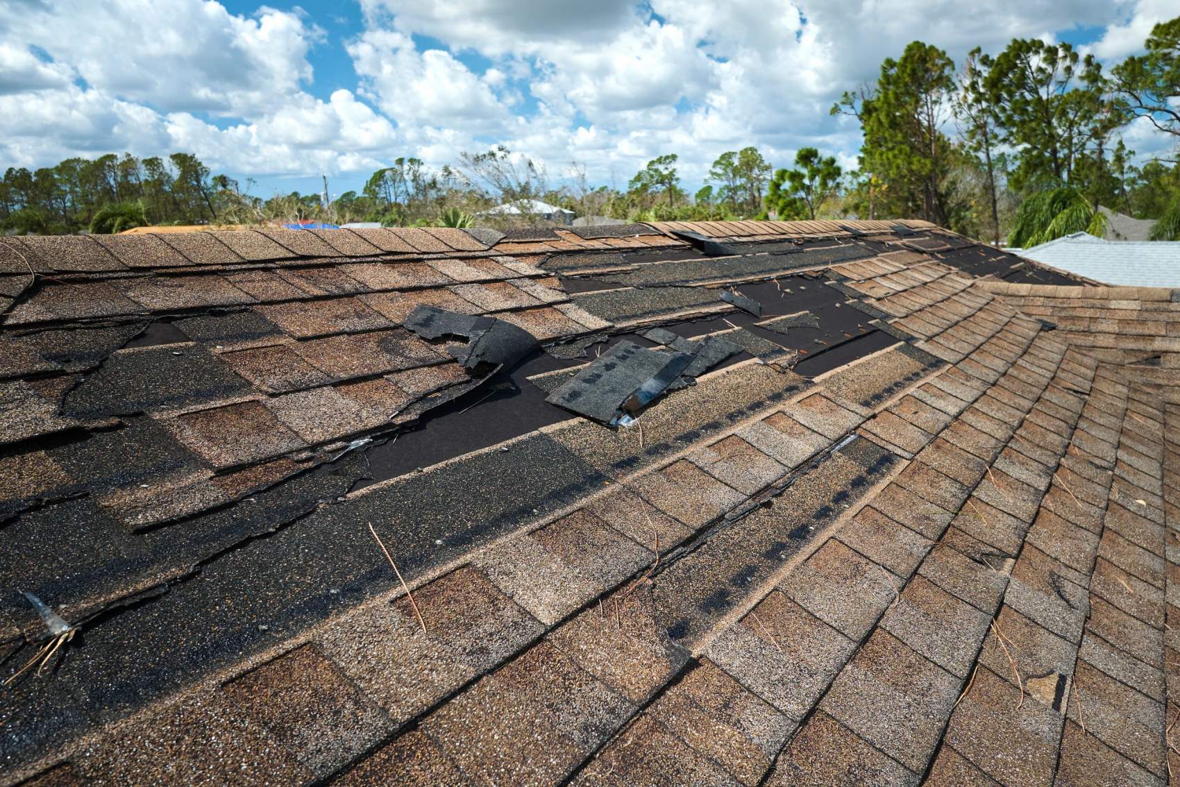 Damaged house roof with missing shingles after hurricane Ian in Florida. Consequences of natural disaster.